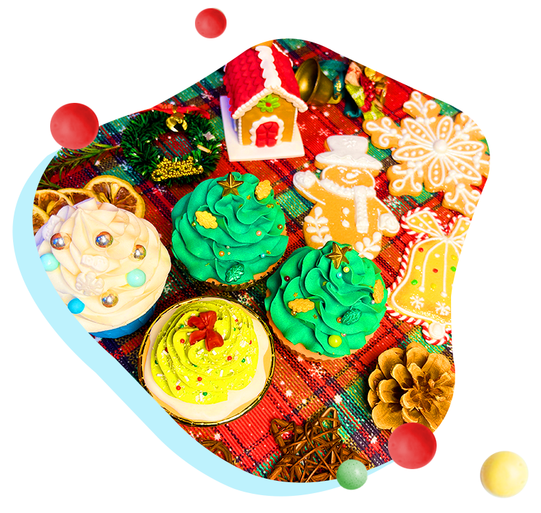 Festive Christmas-themed cupcakes with colorful icing and decorative elements, surrounded by holiday cookies and ornaments on a plaid tablecloth.