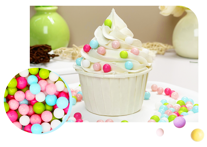 A delectable cupcake crowned with white icing and embellished with colorful cake sprinkles, complemented by a variety of cake decoration candies scattered around.