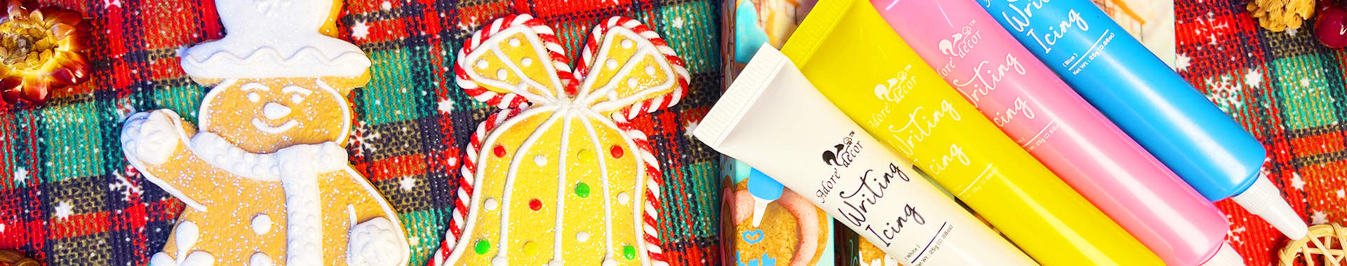 Gingerbread cookies with colorful icing and festive sprinkles, accompanied by tubes of writing icing in yellow, pink, and blue, ready to enhance any holiday dessert.