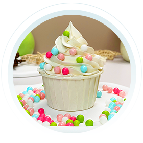 A beautifully decorated cupcake with white icing and colorful sprinkles, surrounded by various cake decoration candies, creating a festive and appetizing presentation.